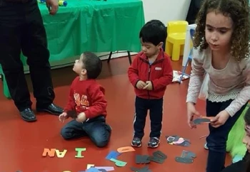 A group of children joyfully playing with colorful letters and numbers spread out on the floor, fostering early learning A group of children joyfully playing with colorful letters and numbers spread out on the floor, fostering early learning